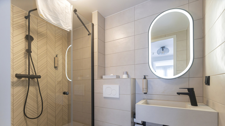 A modern bathroom with an illuminated oval mirror