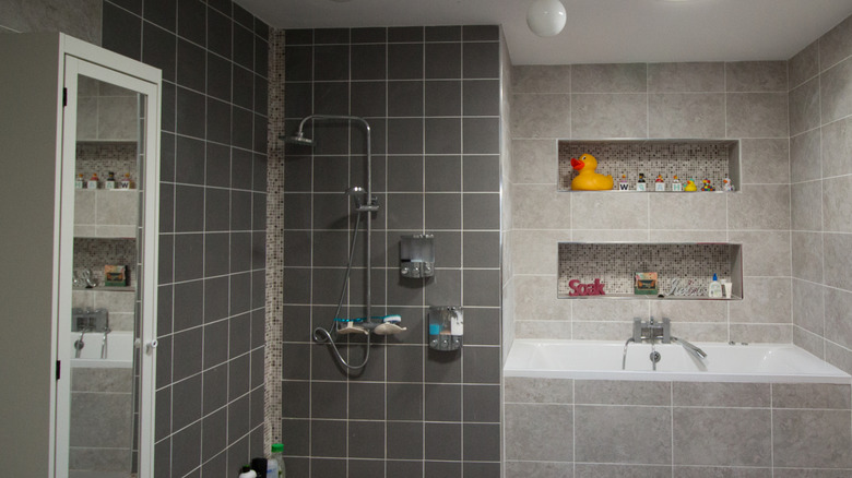 A modern bathroom with large recessed shelves above the bath
