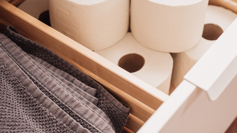 Towels and toilet rolls stored in a bathroom drawer