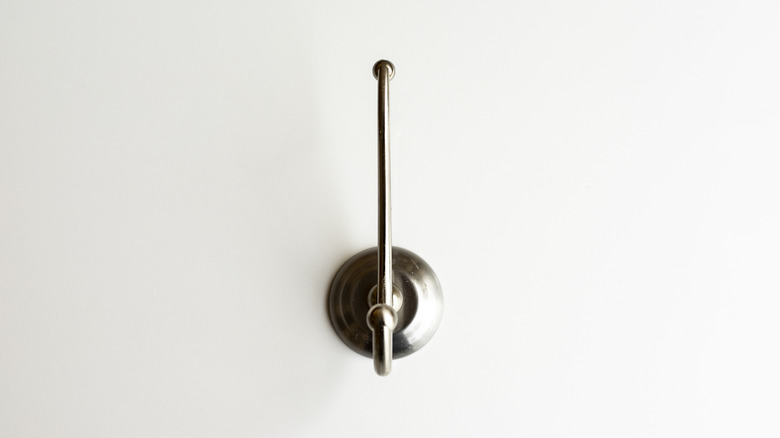 A single decorative metal hook mounted on a white wall