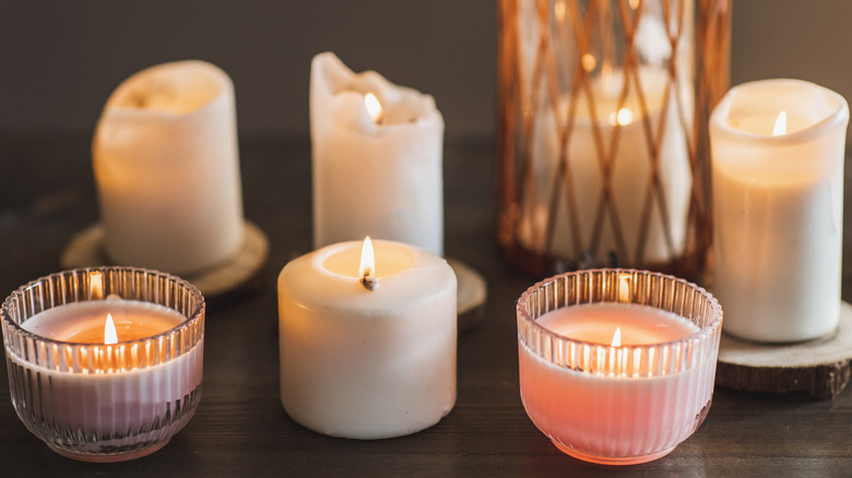 Multiple lit candles sit next to each other on a table