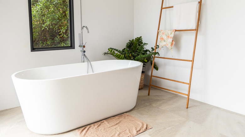 Neutral bright bathroom with freestanding tub and stone floors