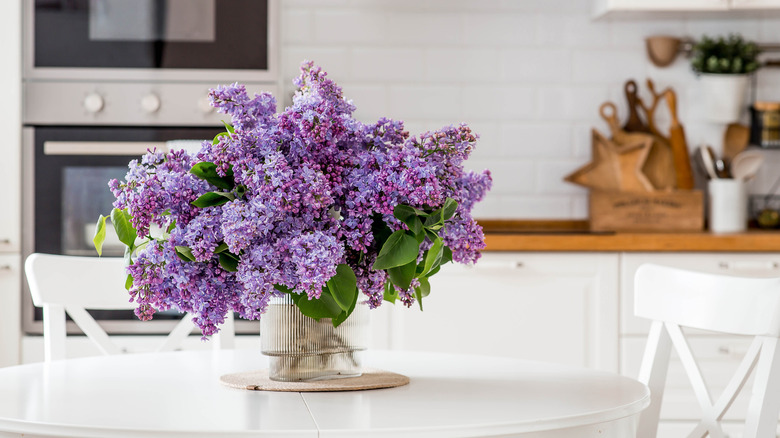 A beautiful bouquet of lilacs on a white table in a glass ribbed vase
