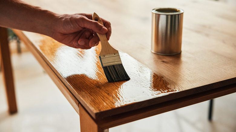 a person using a brush to finish a wood table