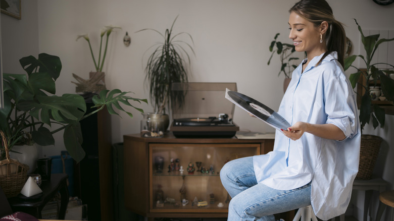A woman smiling while holding a vinyl record in her music nook