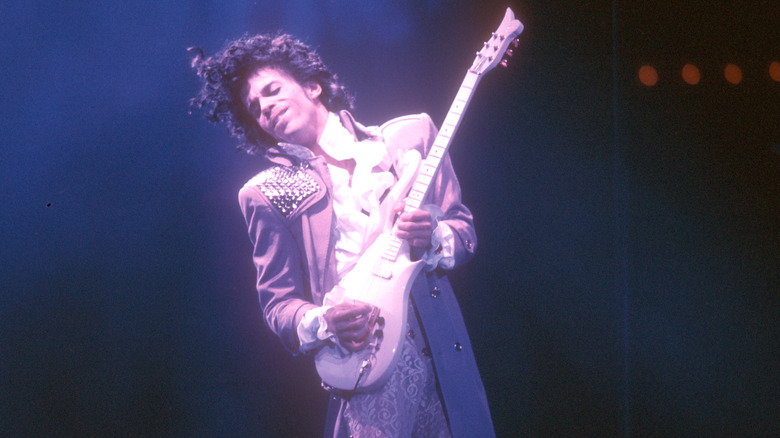 Prince performing onstage and playing a guitar.