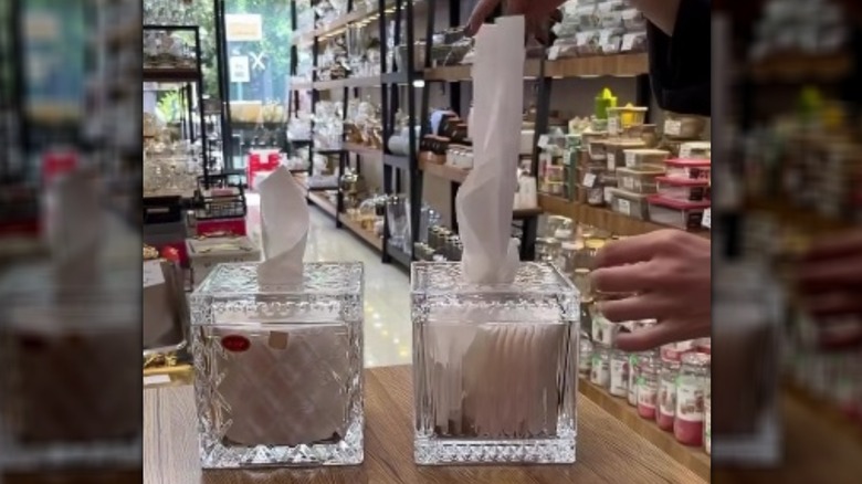 Square glass dispensers with toilet paper and tissue inside.