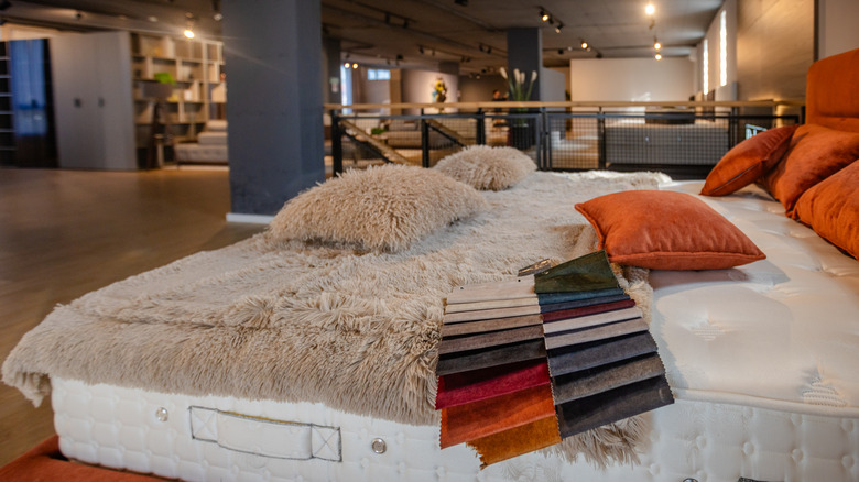 Bed with pillows and a blanket on top of it being displayed in a furniture showroom