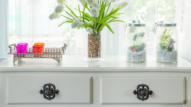 A white dresser with plants and decor on top