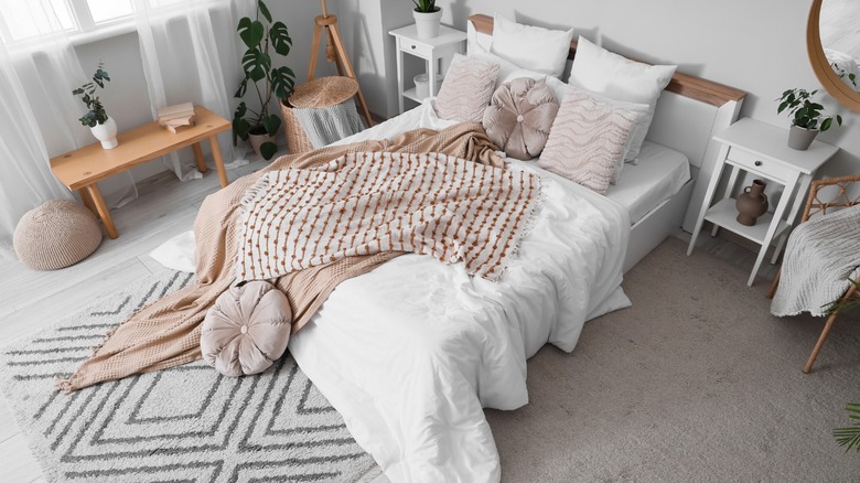 Overhead view of cozy bed with white nightstands and wood details in bedroom.