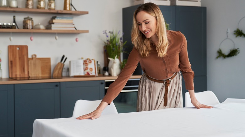woman laying out white tablecloth