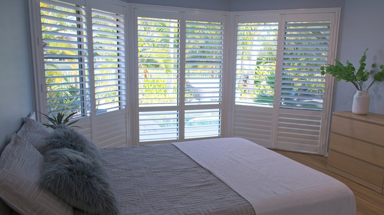 Clean and modern bedroom with large windows and plantation shutters