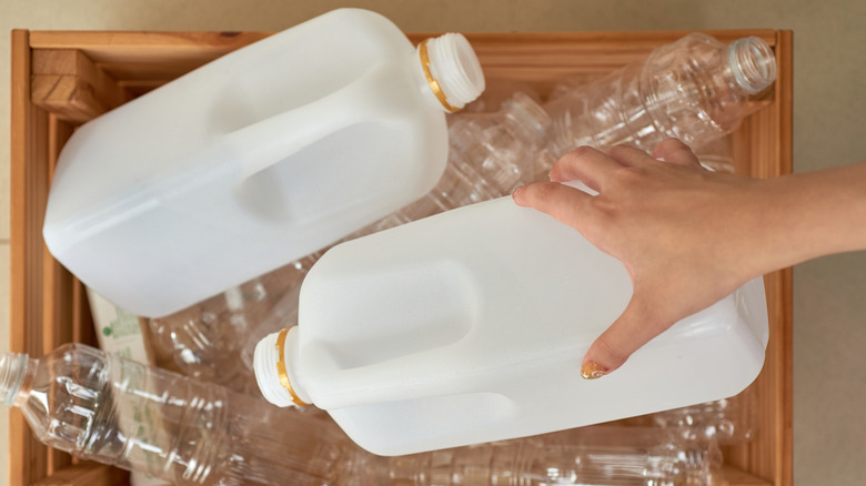 person taking a milk jug out of a reycling crate