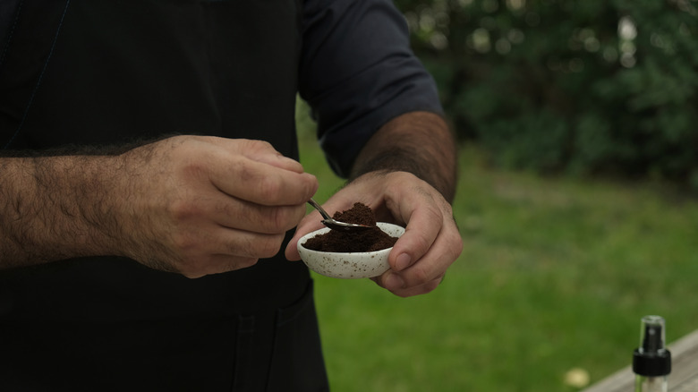 Person sprinkling coffee grounds