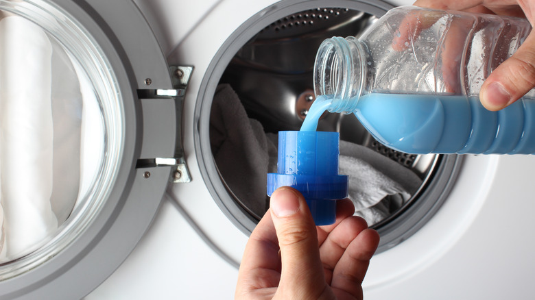 Person pouring laundry detergent into cup