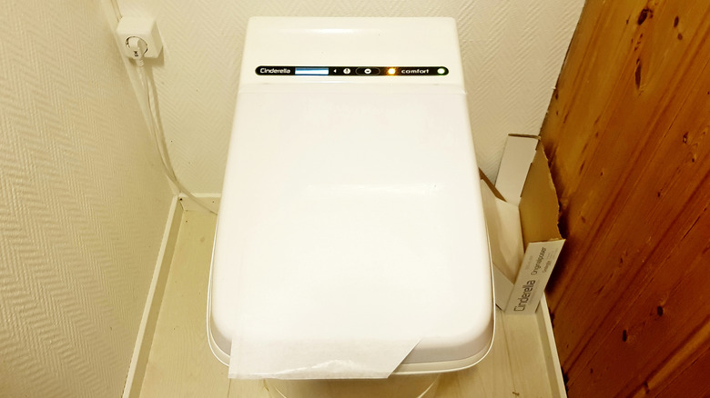 An incinerator toilet with its lid down and a wax paper liner sitting on top