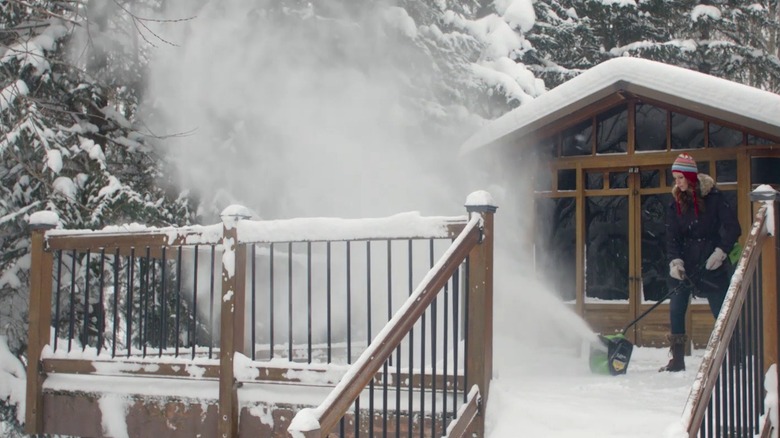 Woman clearing snow from a deck with a power snow shovel