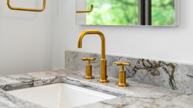 Granite bathroom countertop with gold metal faucet