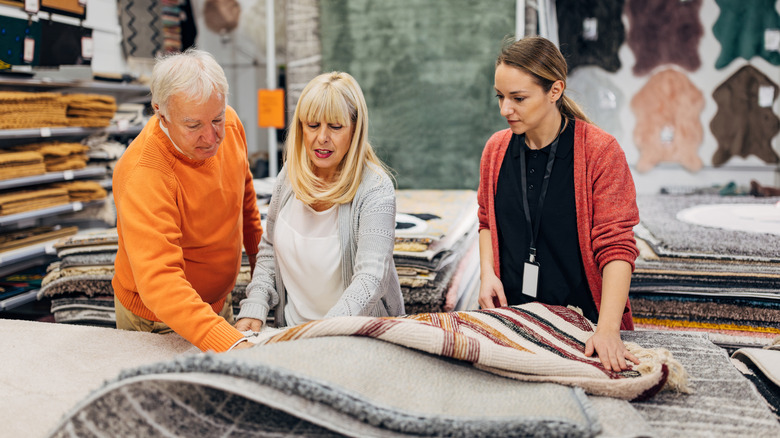 senior couple deciding on carpet to buy in store with salesperson