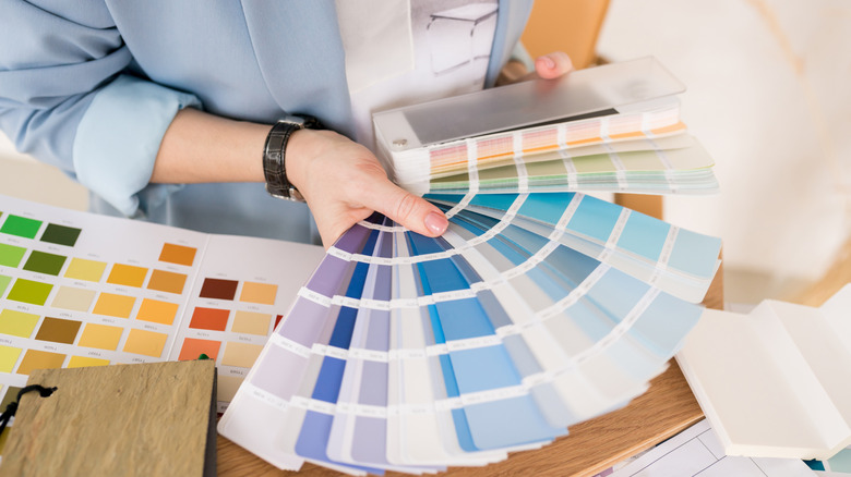 A woman fans out paint swatches, trying to decide which feng shui-inspired color is best to create a vibrant, welcoming kitchen.