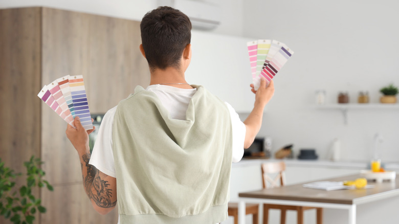 A man looking at paint samples in a kitchen