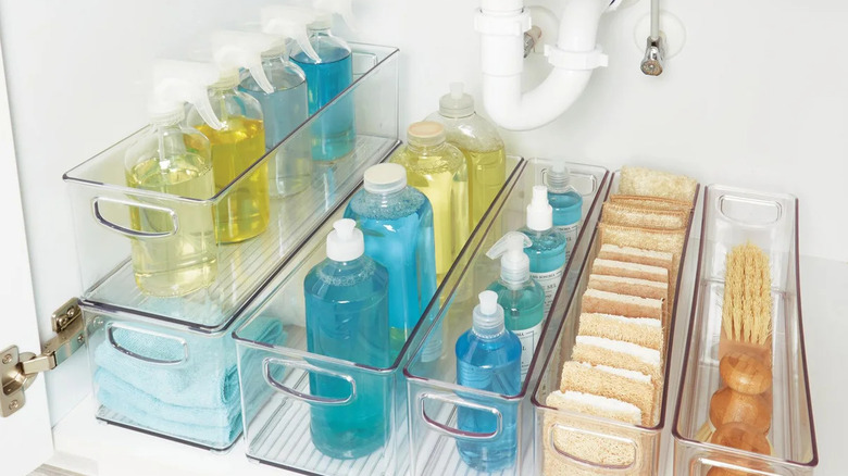 Transparent plastic bins in a cabinet holding cleaning products