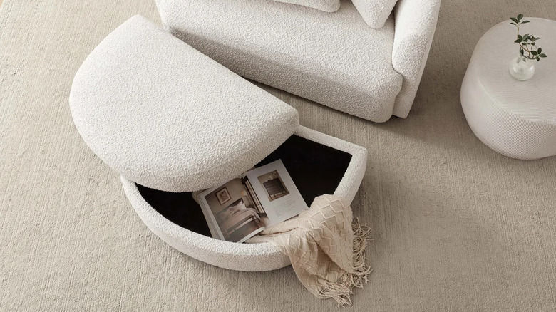 A cream oversized chair and a storage ottoman on a rug