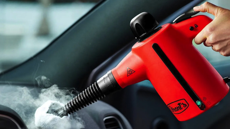 Hand holding a Grant's steam cleaner against a dashboard in a vehicle