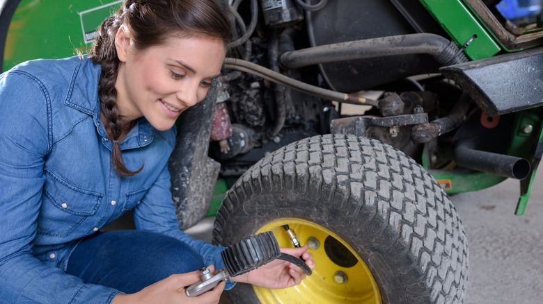 woman checking tire pressure on lawn mower