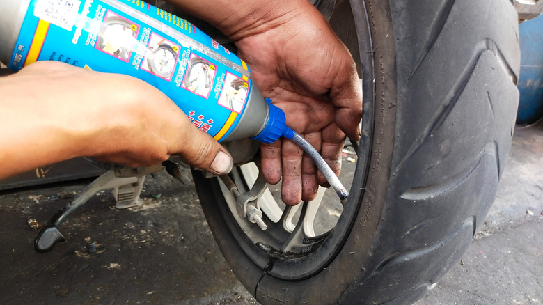 person adding tire sealant to a tire