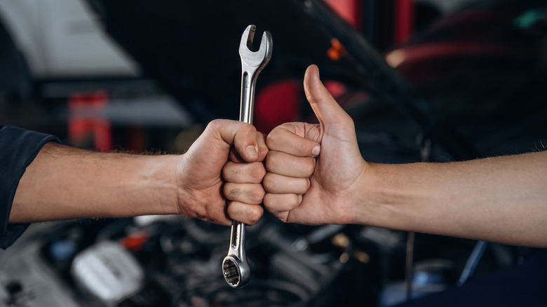 People fist bumping over wrench