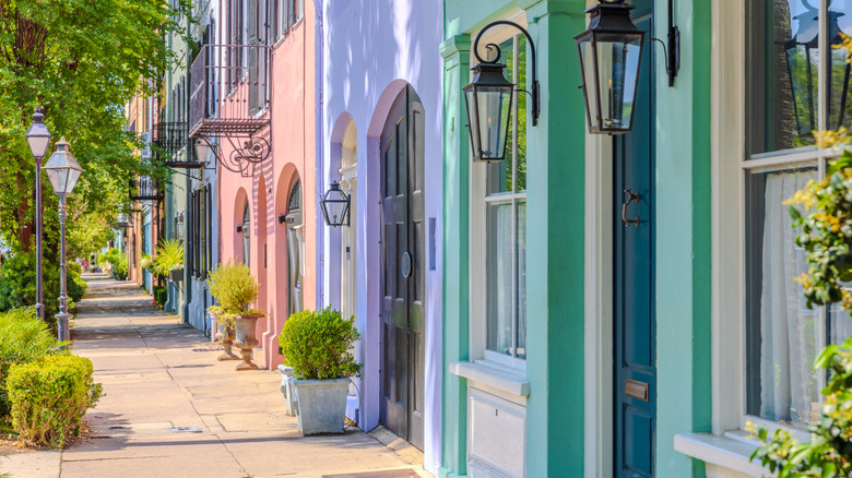 Row of townhouses painted pink, lavender, and green on city street.