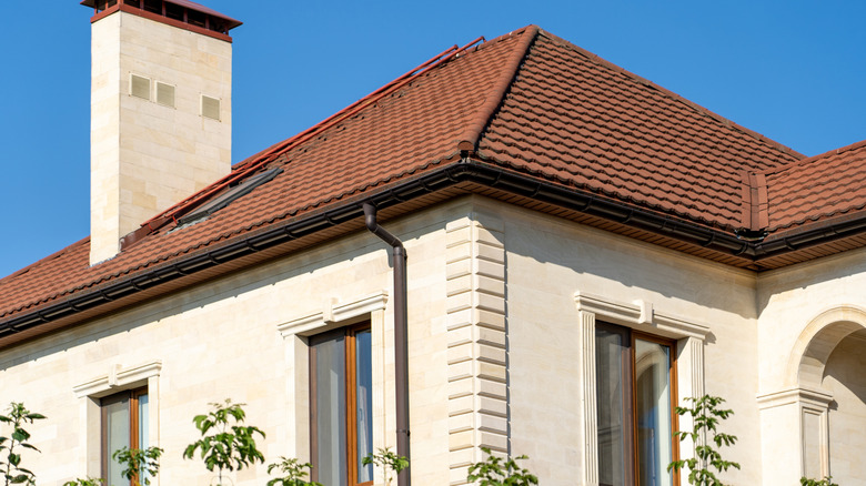 A cream colored house with a reddish brown roof.