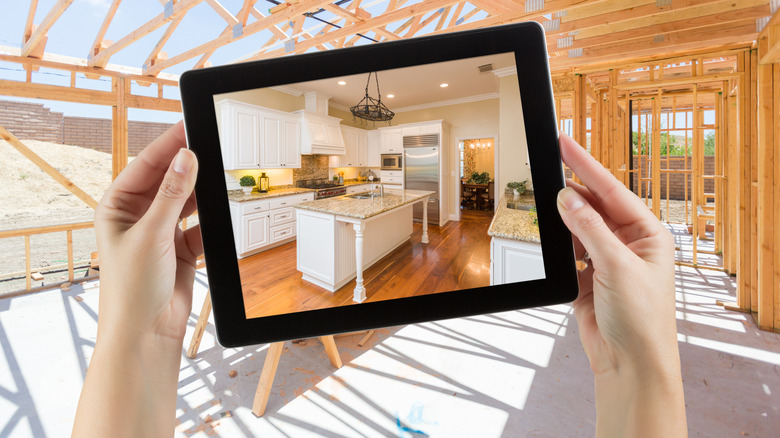 Hands holding a tablet to envision a kitchen in an empty space