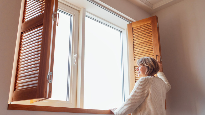 Woman opening interior shutters on a garage window