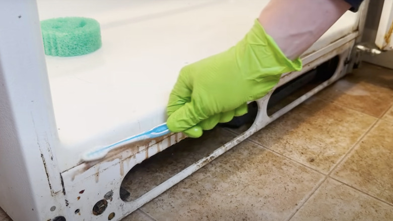 cleaning a dirty refrigerator with a toothbrush