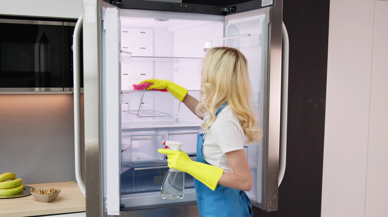 woman with yellow gloves cleaning a refrigerator