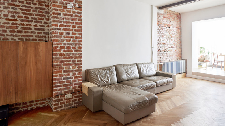 Living room with brick wall, drywall, and a centered gray sofa