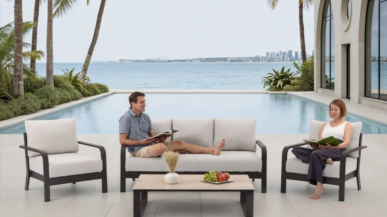 A couple sitting the MoDe Calgary Outdoor Patio Set in front of their swimming pool overlooking a city harbor.