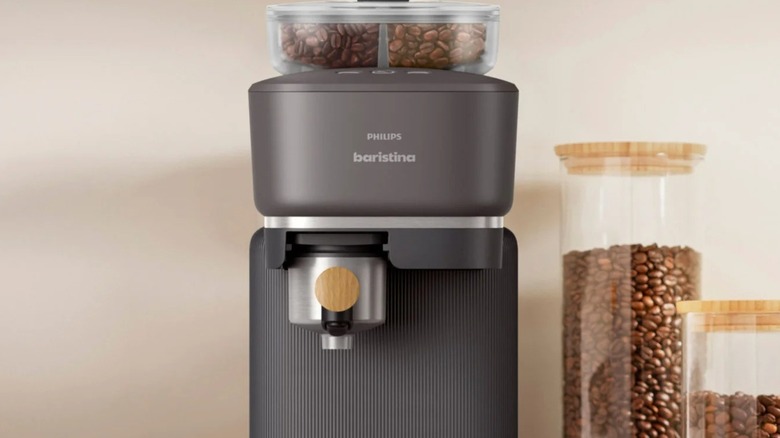 A Philips Baristina Espresso Machine next to a few jars of coffee beans in a kitchen.