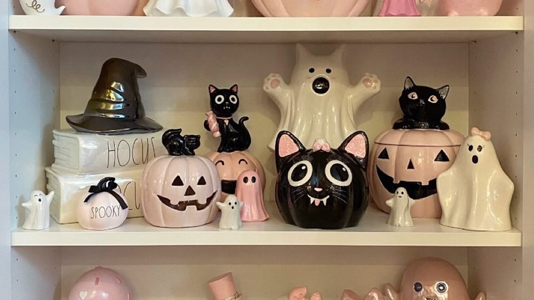 Shelves full of various cute Halloween ceramics in pink, black, and white, including cats, ghosts, and jack-o-lanterns