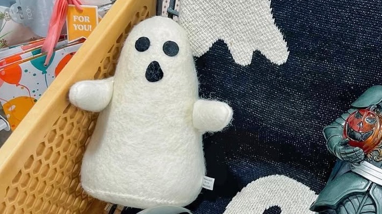 A stuffed ghost facing the camera in a shopping cart with other Halloween decor