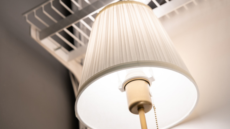 A close up of a lamp shade in a closet with the light turned on