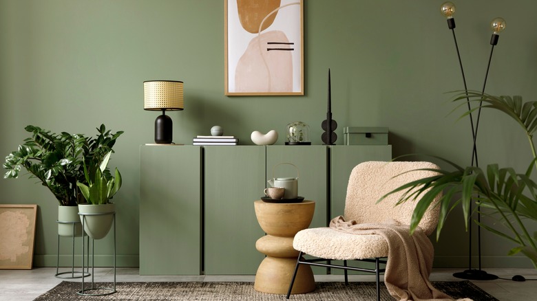 Sage green living room with cream accent chair and plants