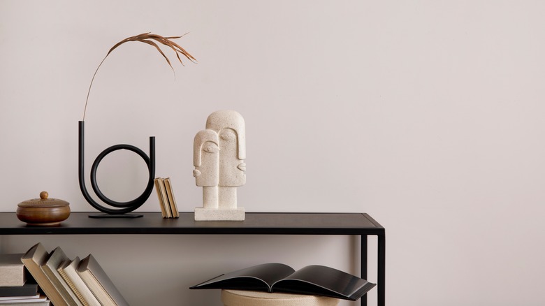 A white two-faced sculpture on a shelf 