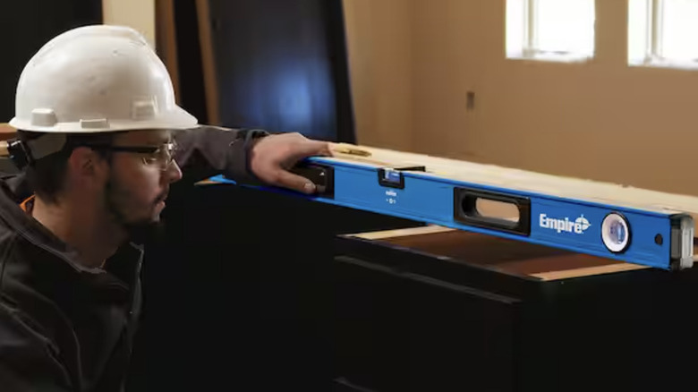 A man uses a 48-inch Empire box level