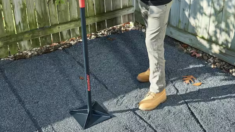 A person uses the Razor-Back steel tamper to level the ground