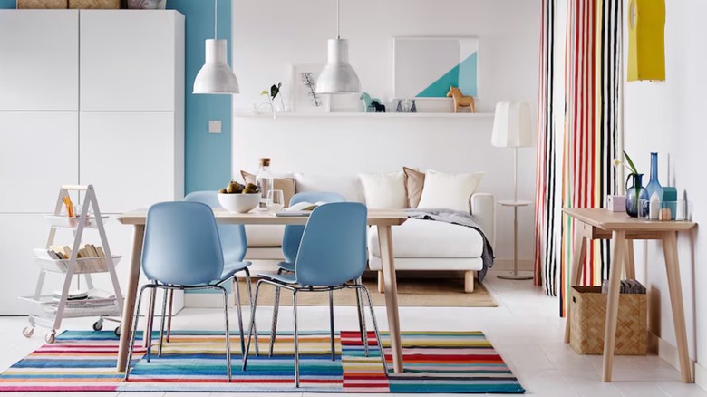 A striped HALVED rug from IKEA lays under a modern dining table in a studio apartment