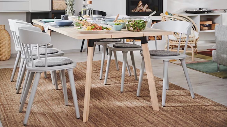 A modern dining table sits on an IKEA LOHALS flatwoven rug