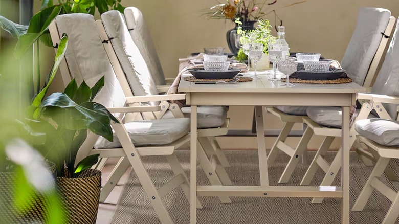 An outdoor dining table and chairs sit on a LYDERSHOLM Indoor/Outdoor Rug from IKEA